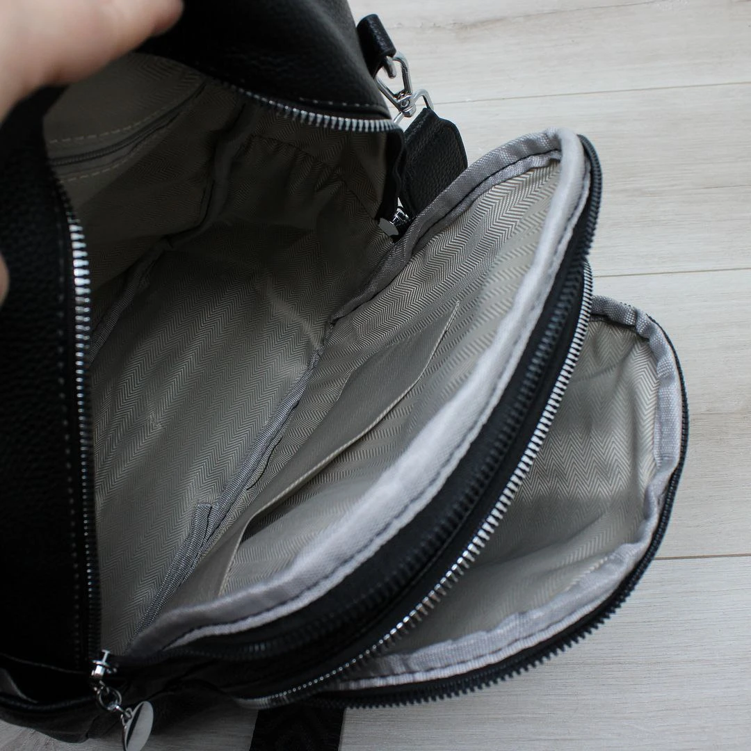 Жіноча чорна сумка-рюкзак з екошкіри з текстильним ременем та срібною фурнітурою