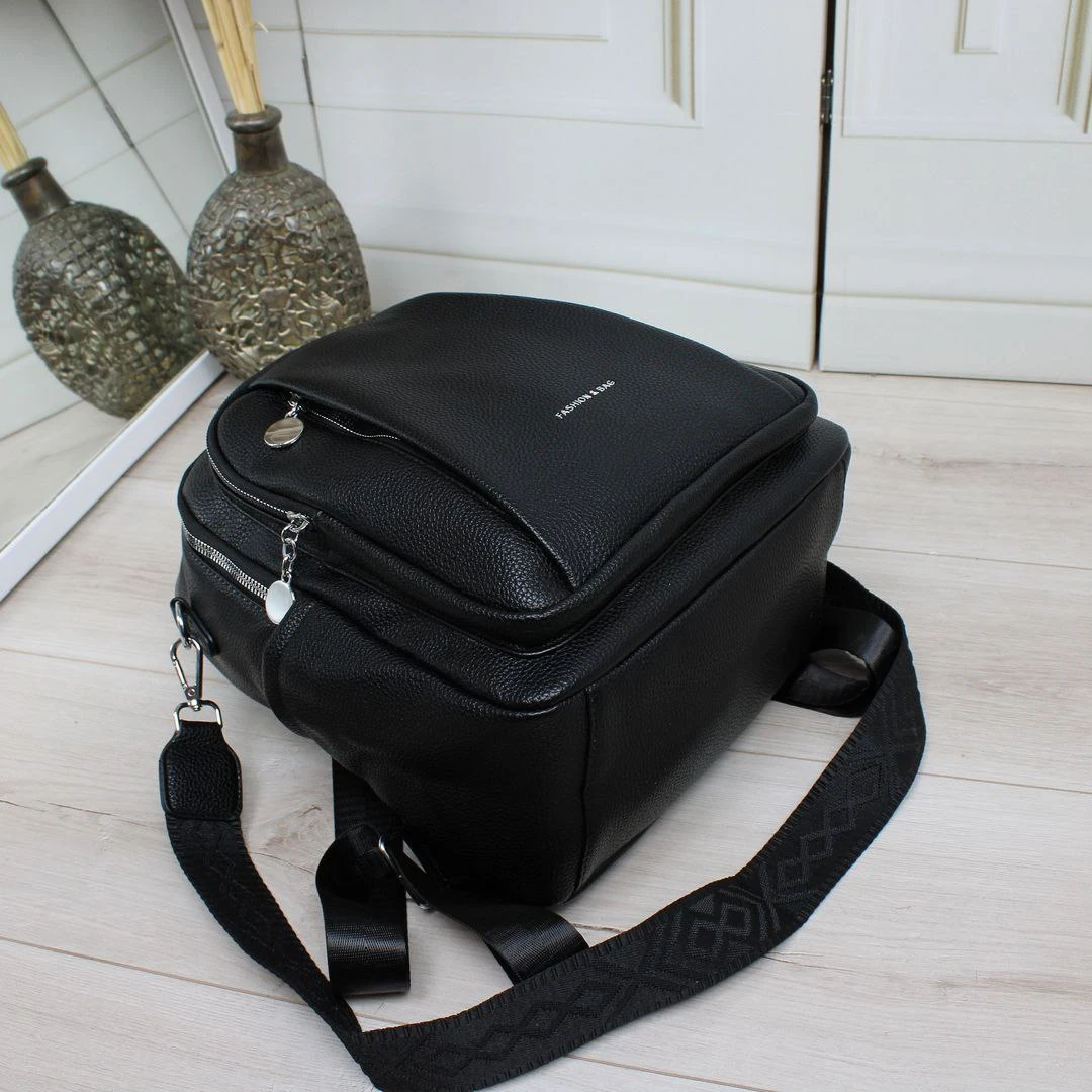 Жіноча чорна сумка-рюкзак з екошкіри з текстильним ременем та срібною фурнітурою